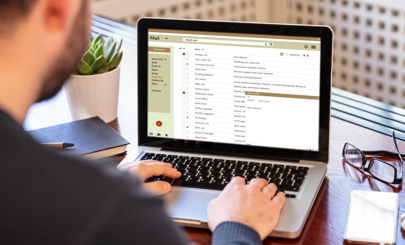 Person composing and sending an email from a laptop